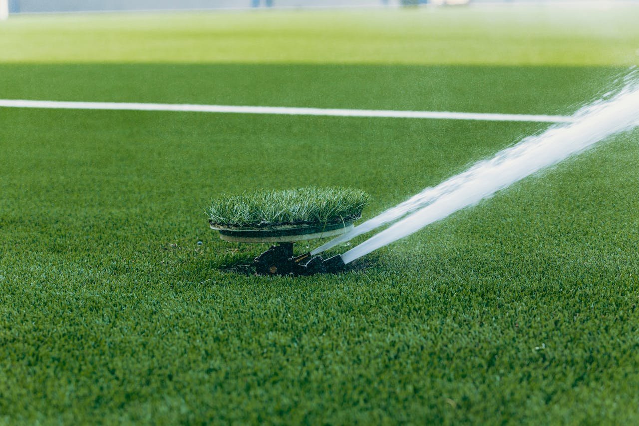 An active sprinkler watering a vibrant green sports field, enhancing the lush grass surface.